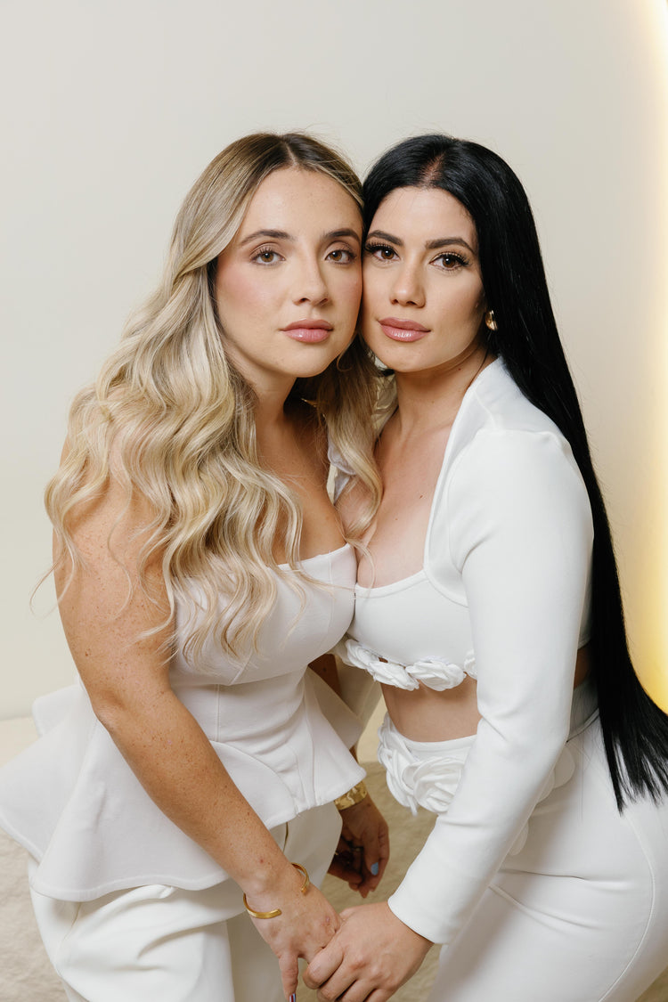 Dos modelos abrazadas con extensiones de cabello: rubio ondulado y negro liso largo - Popa Emperifolla Beauty Studio